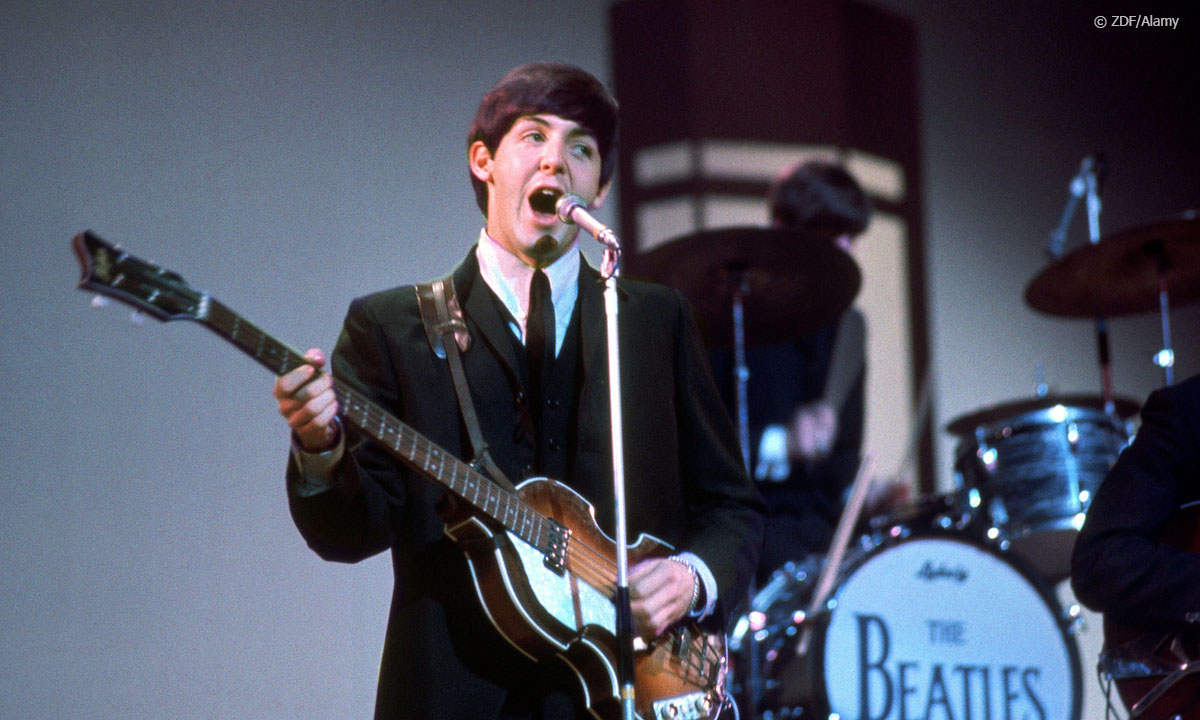 ZDFzeit: Mensch Paul McCartney! - Der ewige Beatle: Paul McCartney als junger Mann hält seinen Bass in der Hand und schaut zur Seite.