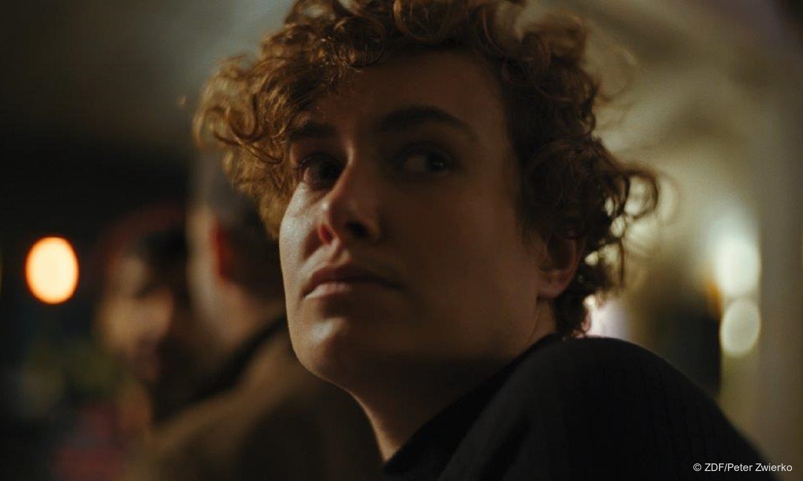 "Ab 18! - Being Sascha": Porträtaufnahme einer jungen Person mit kurzem lockigem Haar im Halbdunkel. (c) ZDF/Peter Zwierko