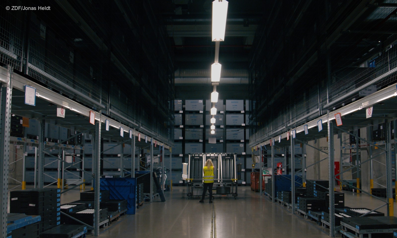 "Ab 18! - Seda baut Autos": Riesige Fabrikhalle in der Supertotalen, am Ende sieht man ein Mädchen von hinten. (c) ZDF/Jonas Heldt