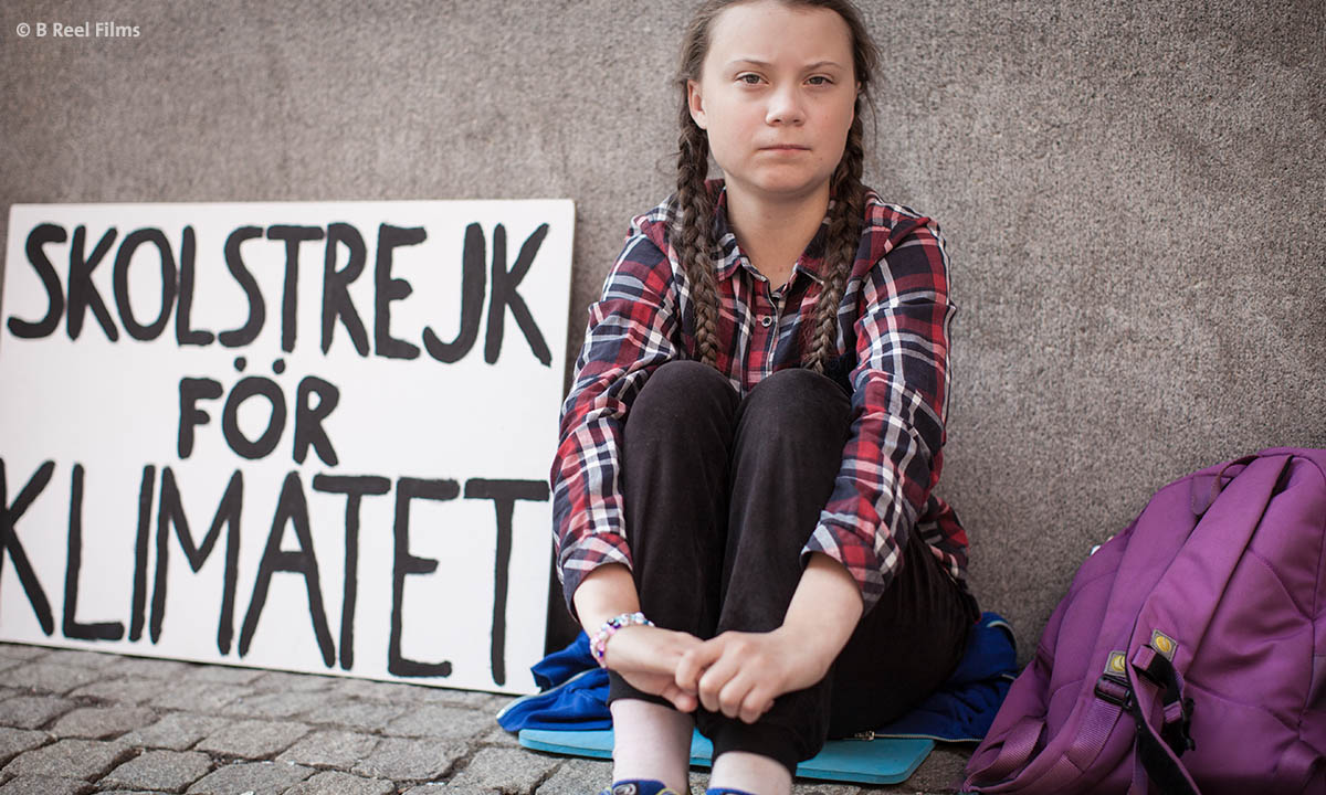 Greta Thunberg sitzt während ihres Schulstreiks vor einem Gebäude.