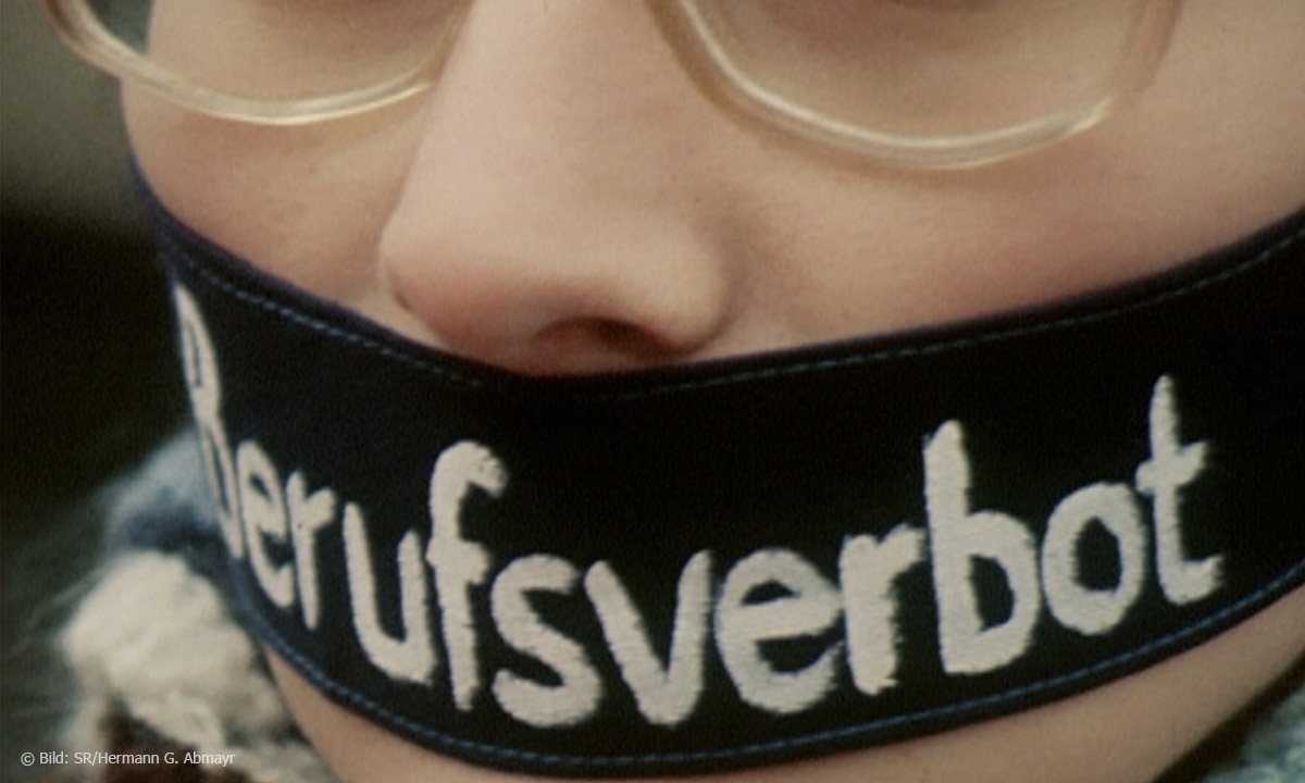 Foto von jungem Menschen mit Brille und schwarzer Binde um den Mund, auf der "Berufsverbot" steht, Bild: SR/Hermann G. Abmayr